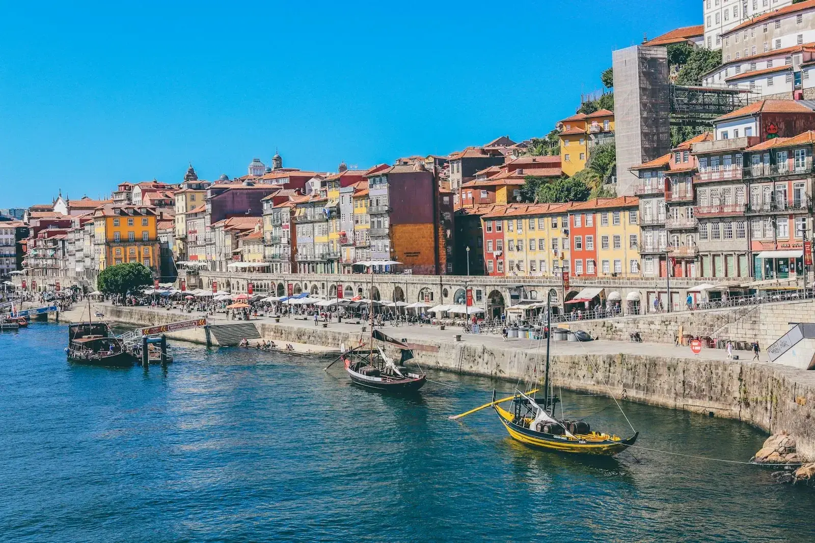 Aerial view of Lisbon's pastel rooftops and the Tagus river at golden hour, illustrating Portugal as a destination for remote workers and relocated employees.