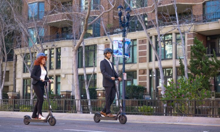 a man and a woman riding scooters on a city street