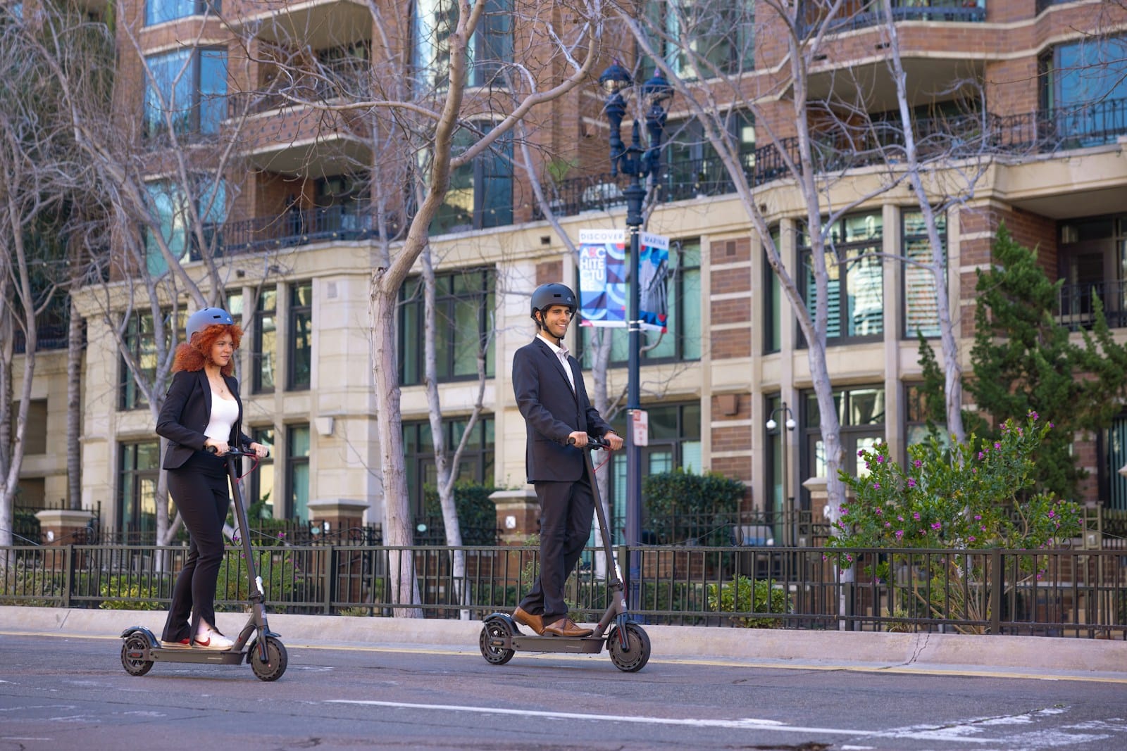 a man and a woman riding scooters on a city street