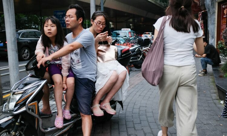 man riding motor scooter with two girls
