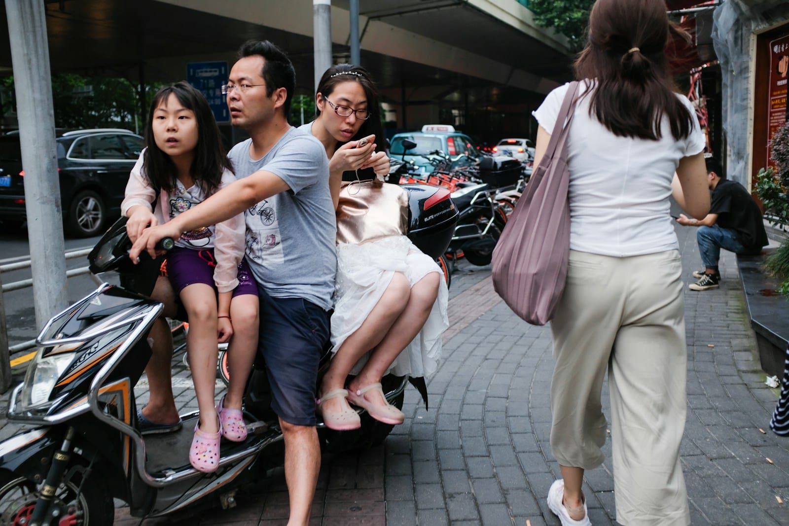 man riding motor scooter with two girls
