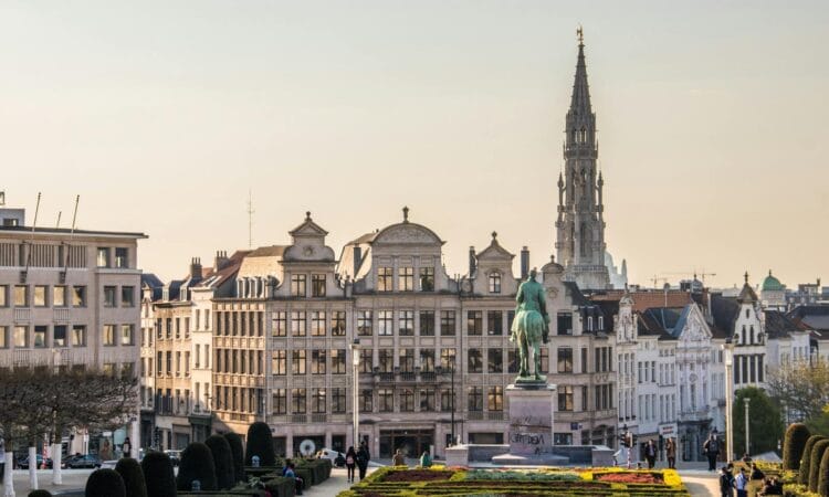 A beautiful cityscape of Brussels with the iconic Town Hall tower and vibrant gardens.