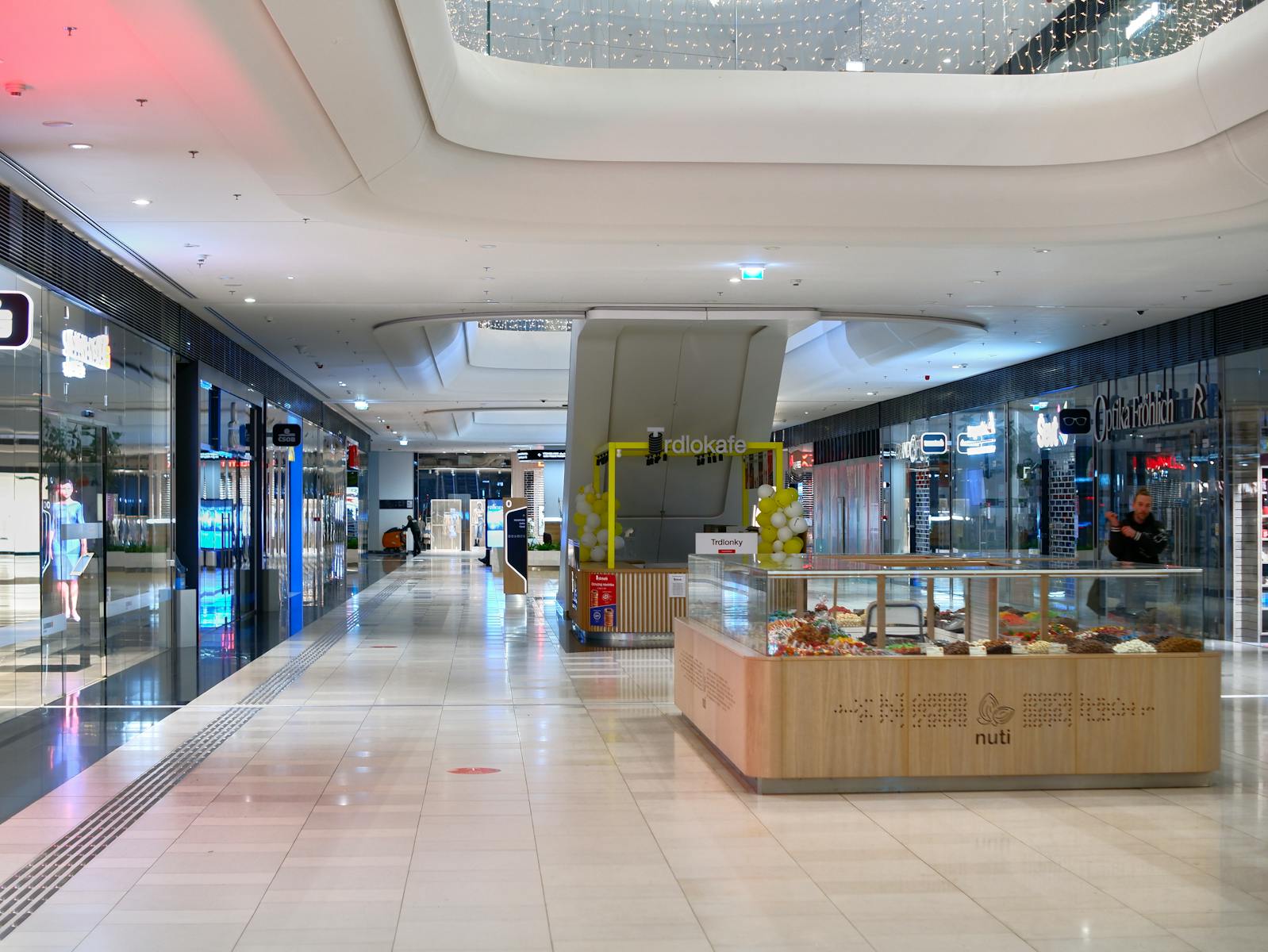 Spacious shopping mall interior in Bratislava with shops, escalators, and vibrant lighting.