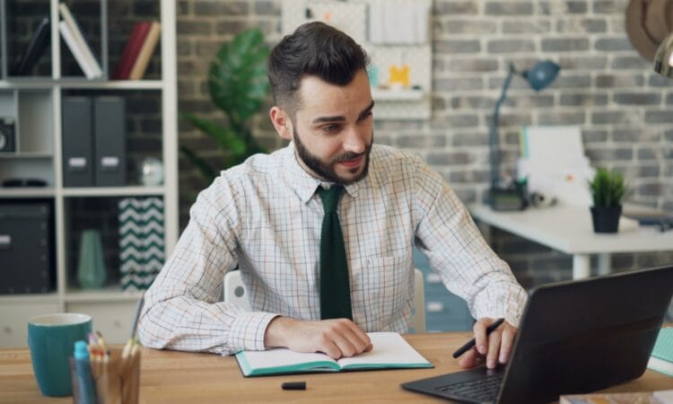 a man sitting at a desk working on a laptop