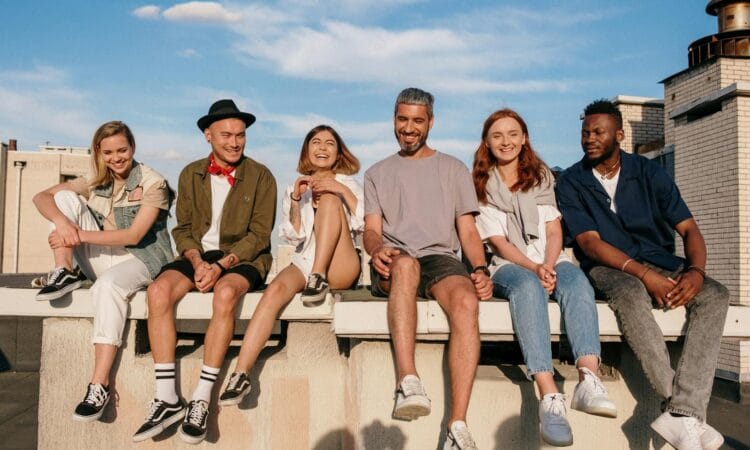 Diverse group of friends laughing and relaxing on a sunny rooftop.