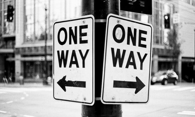 a one way sign on a pole on a city street