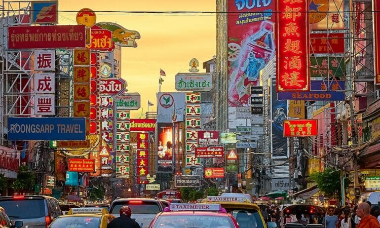 vehicles on street between buildings with Kanji script signage during golden hour