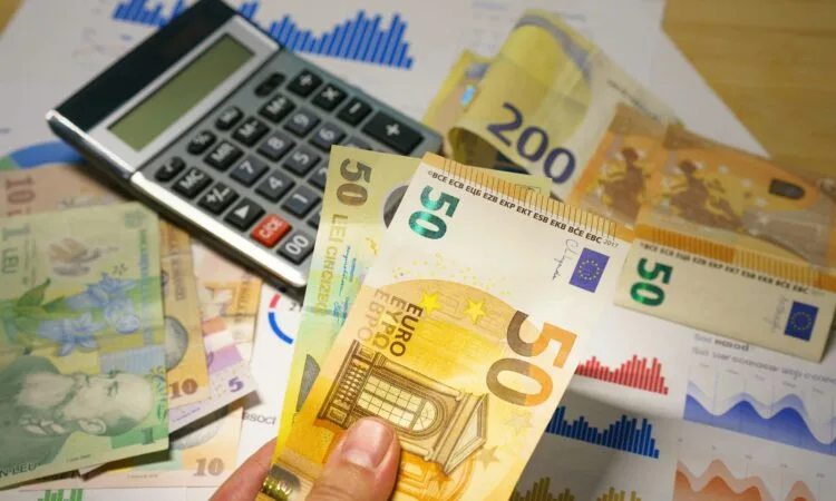 A person holding a bunch of money next to a calculator