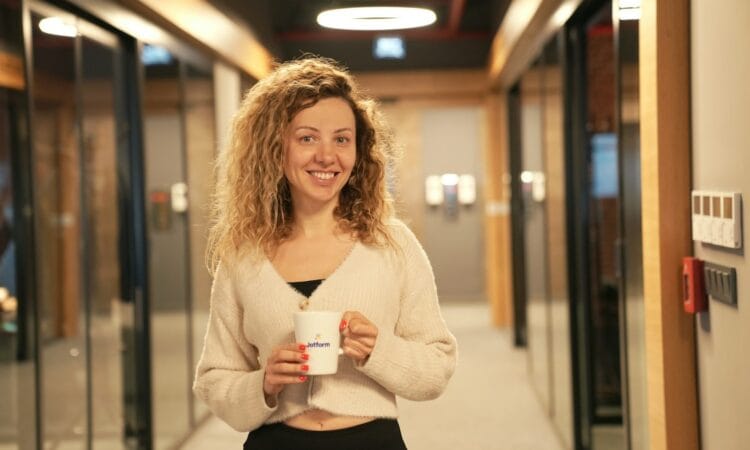 a woman holding a cup of coffee in a hallway