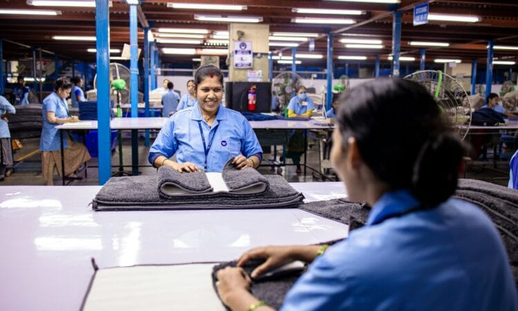 Factory workers are folding textiles at a workplace.