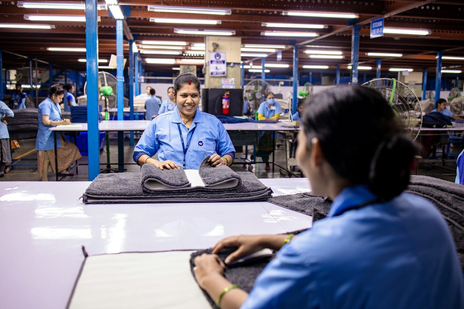 Factory workers are folding textiles at a workplace.