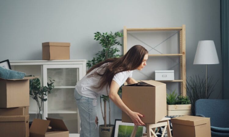 a woman moving boxes in a living room