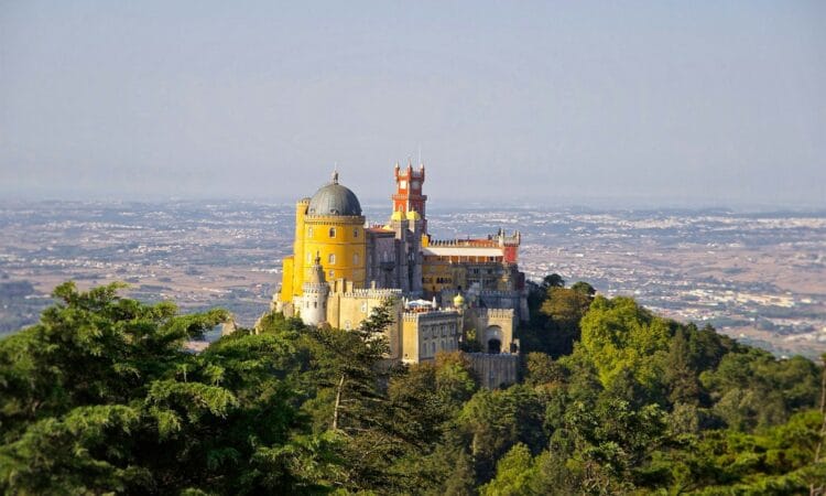 gray and yellow castle at the top of a hill