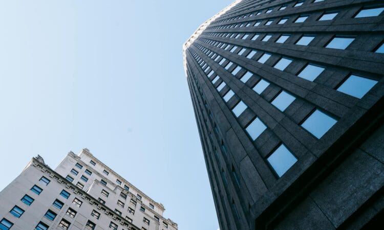 Upward view of modern skyscrapers with a clear blue sky, showcasing contemporary architecture.