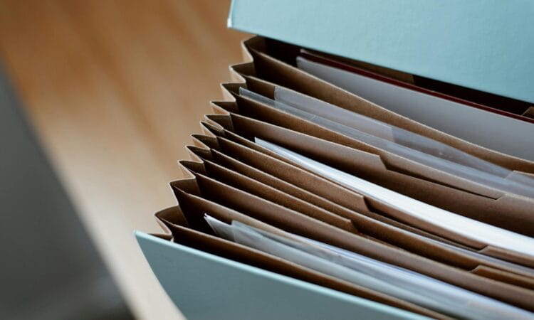 High angle of opened briefcase for documents with papers accosted in order placed on wooden table