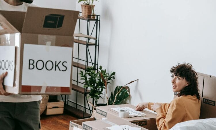 A couple packs boxes labeled books while preparing to move to a new home.