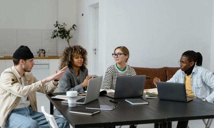 Group of diverse colleagues collaborating with laptops in a modern office setting.