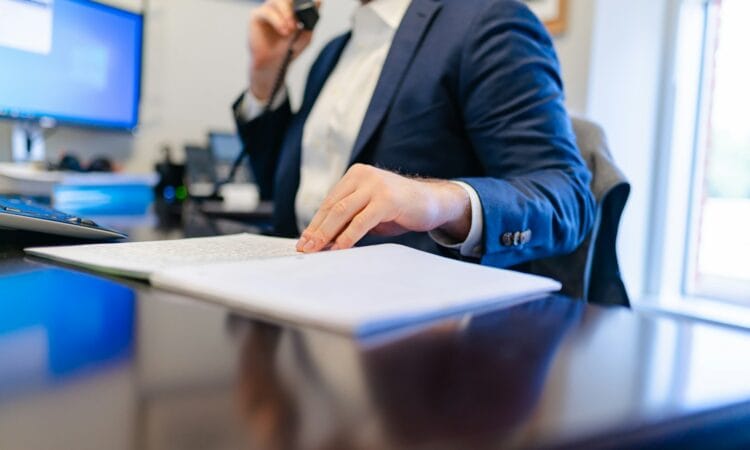 a man sitting at a desk writing on a piece of paper