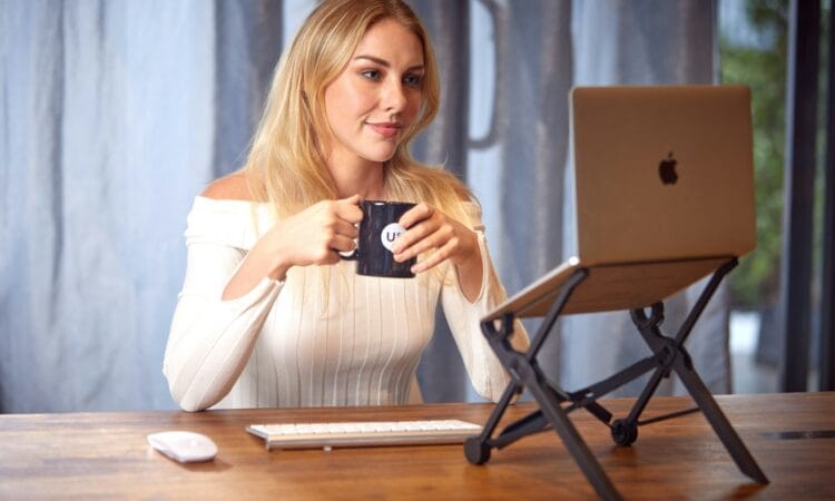 a woman sitting at a table with a laptop and a cup of coffee