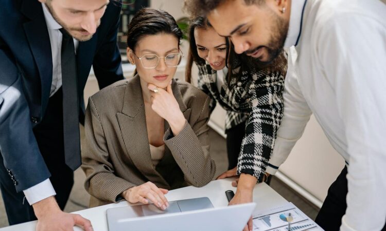 Business team collaborating around a laptop in a modern office environment.