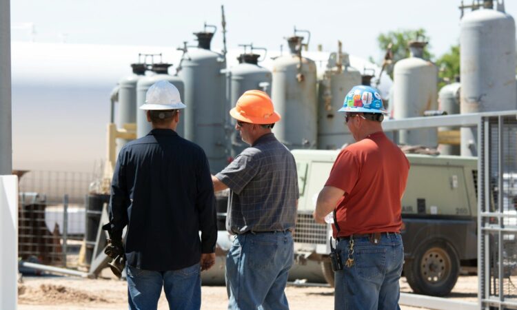 man in black jacket standing beside man in orange shirt