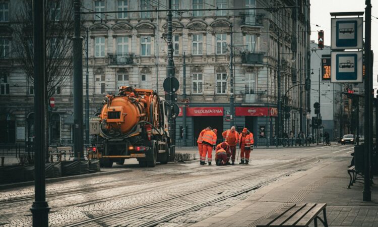 City workers repairing tram tracks on Piotrkowska Street in Łódź, Poland, amidst classic architecture.