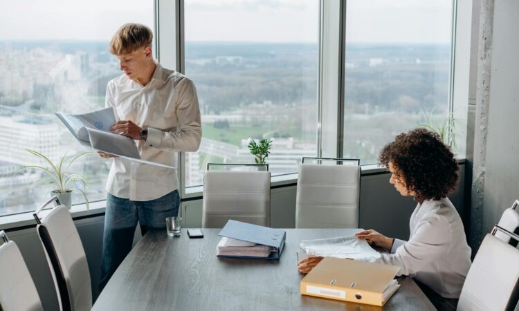Business professionals reviewing documents in a modern office with city view, teamwork and collaboration concept.